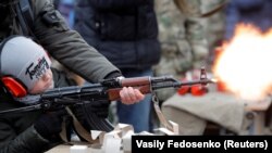 Беларус милициясынын кызматкери  өспүрүмгө автомат атканды үйрөтүүдө. 2020-жыл