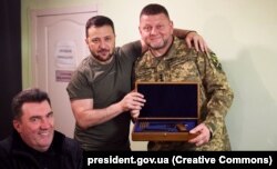 Президент України Володимир Зеленський, головнокомандувач ЗСУ Валерій Залужний (праворуч), який отримав від глави держави Володимира Зеленського (у центрі) нагородну зброю, і секретар РНБО Олексій Данілов (ліворуч). Дніпро, 27 липня 2023 року