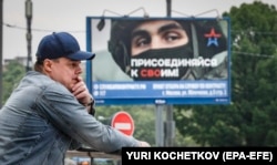 Rus ispred plakata sa sloganom 'Pridruži se', kojim se reklamira vojna služba, u Moskvi, 25. maja 2023.