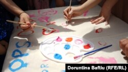 Fëmijët duke pikturuar mbi një pëlhurë gjatë aktiviteteve në qendrën e The Ideas Partnership për Ditën Ndërkombëtare të Fëmijëve.