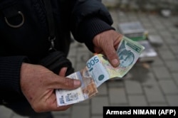 Një person në Graçanicë mban në duar dinarë serbë më 1 mars 2024.