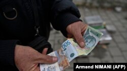 Një shitës lokalë në Graçanicë mban në duar dinarë serbë. 1 mars 2024. 