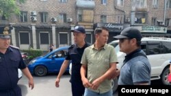 Улукбек Карыбек уулу милиция кызматкерлеринин коштоосунда кетип баратат. 