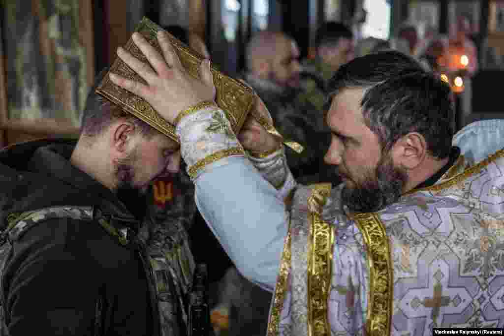 Ukrainian soldiers receive a blessing during Christmas Eve mass on December 24 near the city of Kupyansk in the Kharkiv region. Kyiv is defying Moscow as it celebrates Christmas for the first time on December 25 instead of on January 7, the day observed by the Russian Orthodox Church.&nbsp;