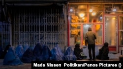 یو شمېر بې وزله افغانې مېرمنې په تیاره ماښام د مرستې په هیله د یوه نانوایي مخې ته ناستې دي - تصویر له ارشیفه 