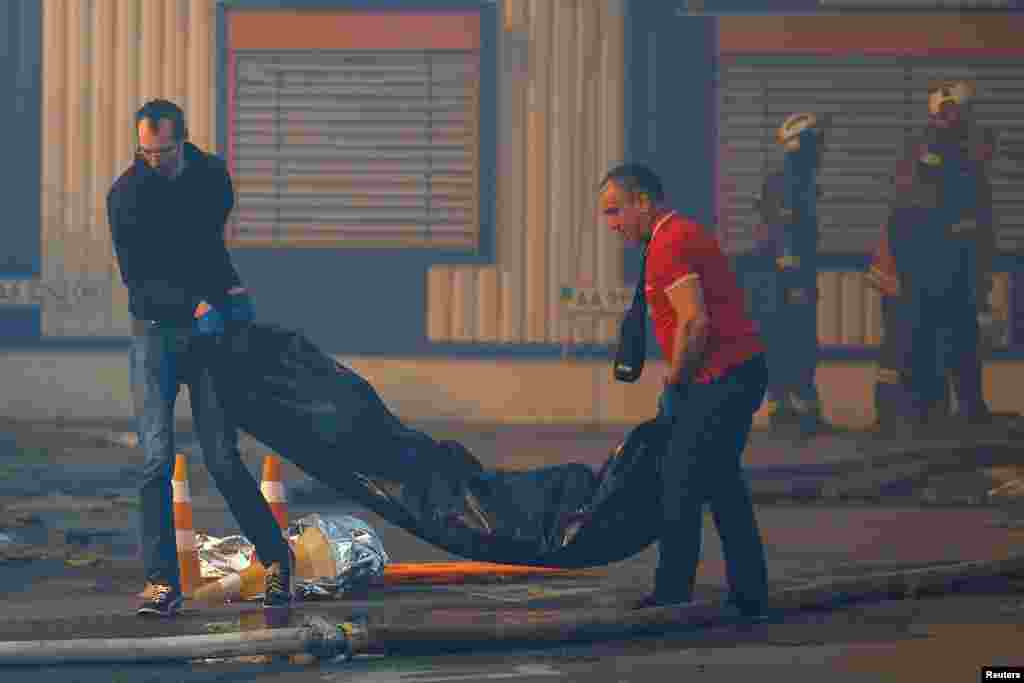 Чоловіки виносять тіло загиблої людини з місця влучання