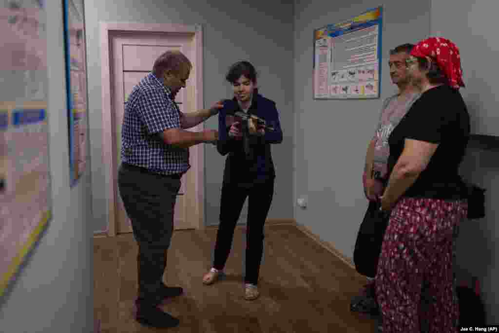 Oghirenko o învață pe Viktoria Ludciak cum să mânuiască arma în timp ce ceilalți participanți privesc. Deși Kievul nu se află în prezent în primele linii ale războiului, riscul minelor lăsate în urmă de ruși, care au ocupat pentru scurt timp zone de la periferia capitalei în primele zile ale războiului, încă persistă. Potrivit Ministerului Afacerilor Interne, aproximativ 451 de mii de kilometri pătrați din Ucraina sunt potențial acoperiți cu mine, adică de aproape două ori suprafața României.