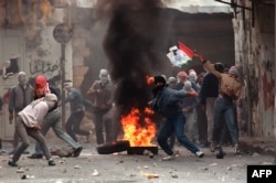 تظاهرکنندگان فلسطینی در ۲۹ ژانویه ۱۹۸۸ در نابلس به سوی سربازان اسرائیلی سنگ پرتاب می‌کنند. انتفاضه اول فلسطینی‌ها در دسامبر ۱۹۸۷ آغاز شد و تا سال ۱۹۹۳ که توافقنامه صلح اسلو امضا شد ادامه داشت.