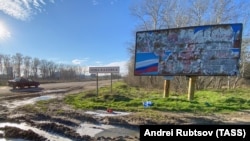 Na saobraćajnom znaku na rubu grada piše Nova Kakhovka, decembar 2022. Zastava Rusije, čije su snage okupirale Novu Kakhovku od početka potpune ruske invazije na Ukrajinu, vidljiva je na drugom znaku.