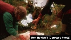 Shqiptarë të Kosovës, që ikën nga shtëpitë e tyre, në Drenicë, duke larë xhenazen e një foshnjeje pesëjavëshe, që vdiq nga kushtet e papërshtatshme në malet e Kosovës, në vjeshtën e vitit 1998, para varrimit të saj.