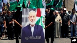 ჰამასის წევრებს უჭირავთ წინა ღამეს მოკლული ლიდერის, ისმაილ ჰანიეს ფოტო, რომელსაც არაბულად აწერია "მოწამე ლიდერი", ალ-ბასის პალესტინელ ლტოლვილთა ბანაკი, ლიბანი, 2024 წლის 31 ივლისი