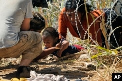 Нелегальні мігранти намагаються пробратися із Мексики у США, долаючи загородження із колючого дроту вздовж річки Ріо-Гранде. Ігл-Пасс, штат Техас. 21 вересня 2023 року