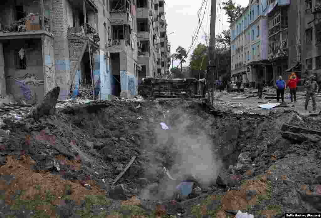 Перевернутий автомобіль видно біля великого кратера після ракетного удару.