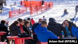 Një grup turistësh shijojnë diellin pranë pistës së skijimit në Bogë.