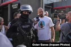 Andrew Tate este escortat de un jandarm la DIICOT, pentru a fi audiat într-un dosar de crimă organizată. 21 august 2024.