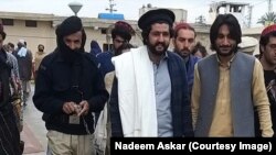 حنیف پښتین (له ښي لوري دویم) عدالت ته د حاضرېدو پر مهال - پخوانی انځور.