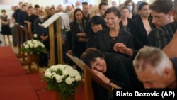 People react next to photographs of the dead during a commemoration ceremony in honor of the victims in Cetinje on August 14.