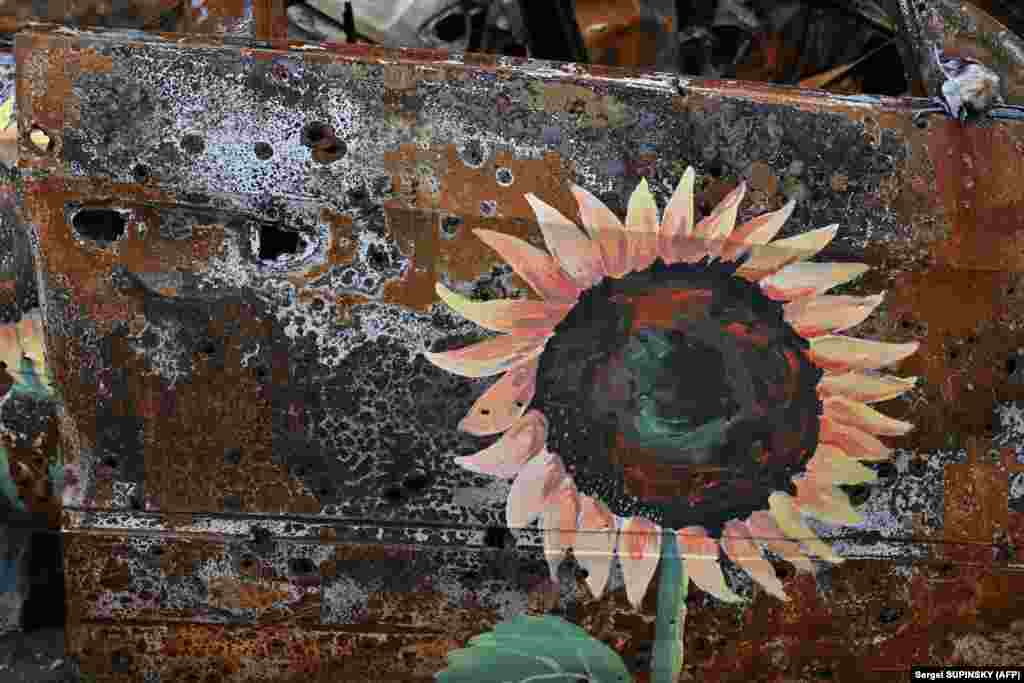 A sunflower, the national flower of Ukraine, is seen on a burned-out car in Irpin, near Kyiv. The installation is causing dismay among some Ukrainians, while others hail the novel approach to raising money for the nation's artistic community, which is languishing during the war.