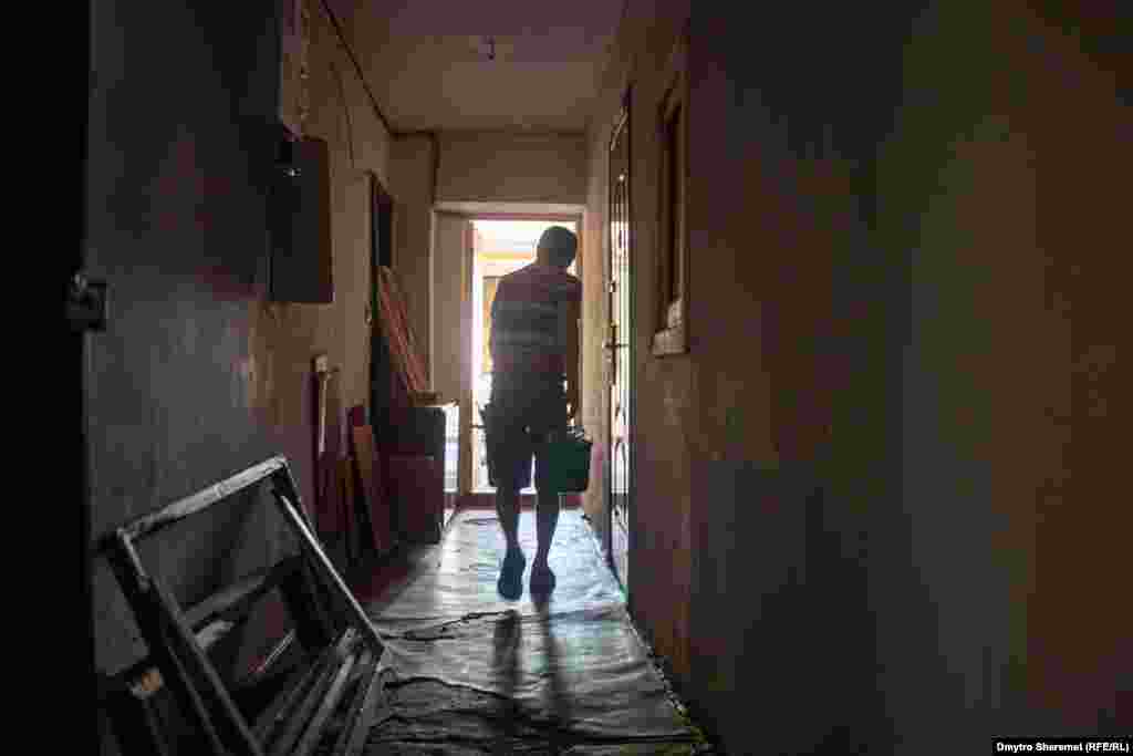 Чоловік&nbsp;виносить шматки розбитого скла&nbsp;зі&nbsp;своєї квартири