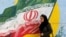 IRAN -- A woman walks in front of a mural painting depicting the Iranian flag, in the capital Tehran. August 6, 2018