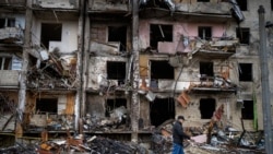 Un bărbat trece pe lângă o clădire avariată în urma unui atac cu rachetă, la Kiev, Ucraina - 25 februarie 2022 (AP Photo/Emilio Morenatti)