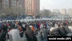 Muncitori de la Foxconn Technology Group, care deține cea mai mare fabrică de telefoane iPhone Apple din lume, în orașul Zhengzhou din provincia Henan, centrul Chinei, se confruntă cu personalul de securitate îmbrăcat în haine de protecție, 23 noiembrie 2022.