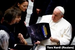 Папа Римський Франциск із календарем «Азовсталь», якого він отримав від Юлії Федосюк, дружини бійця полку «Азов» Арсенія Федосюка, під час щотижневої загальної аудієнції у Ватикані, 21 грудня 2022 року