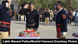 د پولیسو چارواکي د ډېسېمبر پر ۱۸مه په برید کې د وژل شویو ملګرو تر جنازې وروسته تابوتونو ته سلامي کوي. 