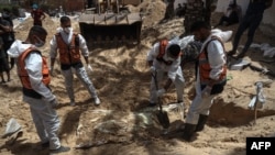 کارمندان صحی در حال بیرون کشیدن اجساد از یک گور دسته جمعی در نزدیکی شفاخانه الناصر دیده میشوند