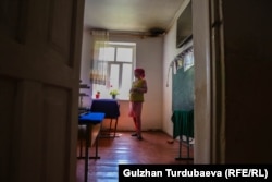 Башталгыч класстын мугалими Айтурган Асан кызы. (Сүрөттүн оң жагындагы бурчта мештин орду байкалып турат).