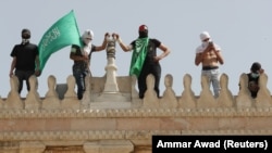 Палестиналыктар ХАМАС тобунун желегин көтөрүп турушат. 10-май, 2021-жыл.