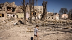 Un copil merge în fața unei școli avariate în orașul Jîtomir, în nordul Ucrainei, 23 martie 2022.