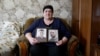 Viktoria Vovk holds portraits of her son and son-in-law. "They tormented our children. For what? They didn't hurt anyone!"