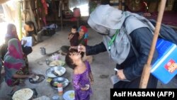 پاکستان کې يوه روغتيايي کارکوونکې يوې ماشومې ته د پوليو ضد څاڅکي ورکوي ـ پخوانی انځور