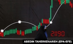 A woman walks past a banner during the 26th International Oil, Gas, & Petrochemical International Exhibition in Tehran on May 13. According to Iran's Oil Ministry, more than 1,000 companies attended the exhibition but many big international companies couldn't participate following U.S. sanctions due to Iran's nuclear program.