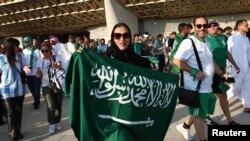 یکی از طرفداران تیم ملی عربستان سعودی در بیرون از استدیوم قطر که بیرق سعودی را به دست گرفته است 