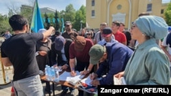 Утилизация алымына қарсы митингіге жиналғандар үкіметке талабы жазылған қарарға қол қойып жатыр. Алматы,  17 сәуір, 2022 жыл.