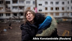 Две женщины плачут во дворе обстрелянного российской армией жилого дома в Харькове, 13 апреля 2022 года