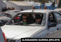 Residents of Mariupol wait at a checkpoint in their damaged vehicle in May.