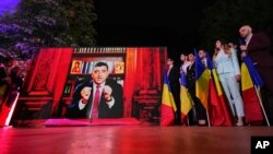 George Simion (AUR) transmite mesajul victoriei în primul tur al alegerilor prezidențiale, de la un birou având în fundal o bibliotecă cu icoane. Nu a venit în fața jurnaliștilor și a colegilor. Cuvintele sale au fost înregistrate și difuzate la ora exit-poll-urilor. 