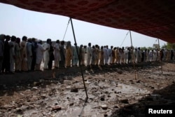 Men fleeing from the military offensive against Pakistani militants in North Waziristan queue to get relief handouts from a storage tent of the World Food Programme in Bannu.