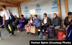 Люди ховаються від сонця та чекають на чергу біля пункту перетину в Станиці Луганській