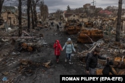 Femeia din imagine se numește Vladislava Liubareț străbate cu greu, împreună cu familia ei și fiica de mână, ceea ce înainte de invazia rusească era o stradă. Când a fost surprisă de fotograful EPA, mergeau să verifice dacă sora ei, aflată în alt cartier, mai este în viață. 6 aprilie 2022.