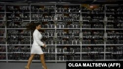 Žena prolazi pored mašina za rudarenje bitkoina na predstavljanju najvećeg centra za kriptovalute u Rusiji, Kriptojuniversa, 2018.