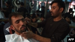 An Afghan barber cuts a customer's hair at a Kabul barbershop prior to the Taliban takeover.