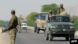 په ډېره اسماعیل خان کې پوځي ګاډي پر سړک تېرېږي، ورسره سرتېرو پر لاره پوسته هم جوړه کړې - پخوانی انځور. 