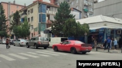 Все в одному фото: затор, жінка переходить дорогу не пішохідним переходом і спортивний автомобіль