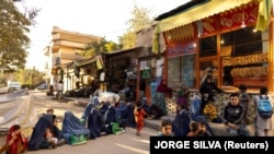 زنان و کودکان فقیر در مقابل یک نانوایی در کابل به امید دریافت خیرات٬ نشسته اند 