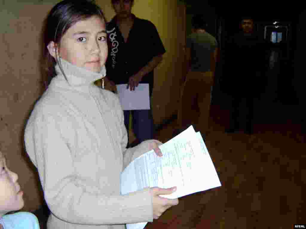 Бұл қыз коммуналдық төлемдер түбіртегін таратуда. Онда су, жылу мен жарықтың ақысы толығымен есептелген.  - Девочка разносит квитанции для оплаты коммунальных расходов. Счета за воду, тепло и свет взыскиваются в полном объеме. 