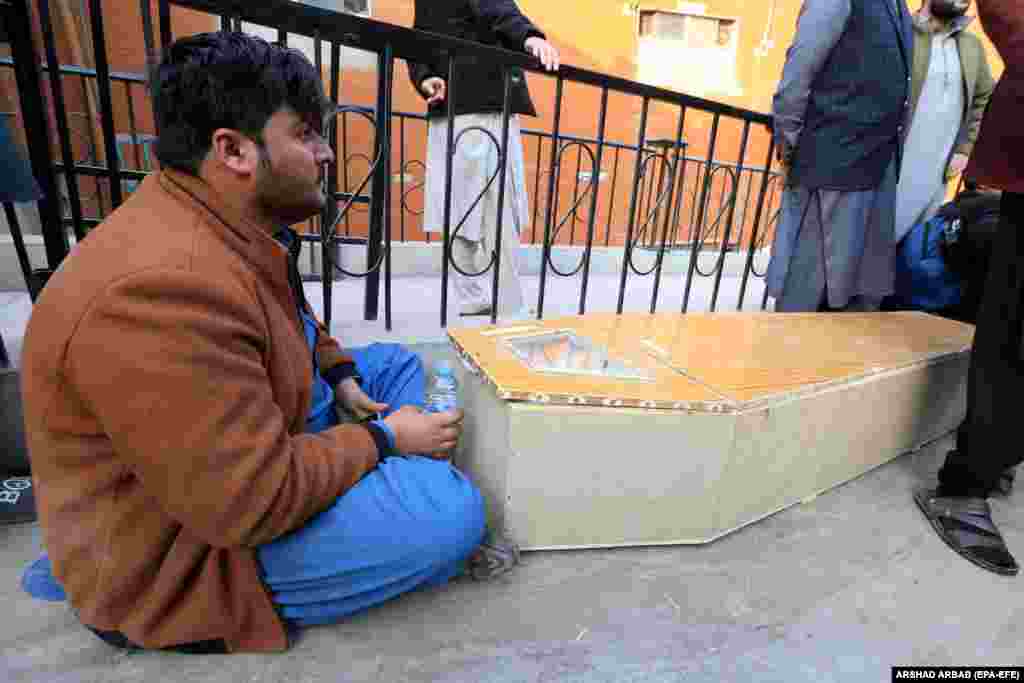 A man sits beside a coffin containing a relative.&nbsp;
